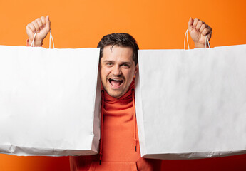 Wall Mural - smiling guy in orange hoodie with shopping bags