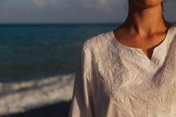 Wall Mural - woman in a light dress sea sunset reflection.body part fragment on a background of the sea