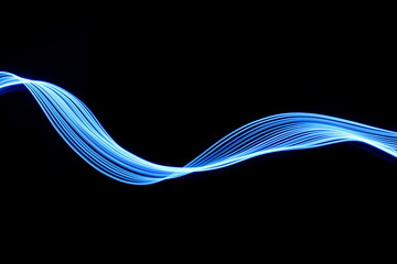 Wall Mural - Long exposure photograph of neon blue colour in an abstract swirl, parallel lines pattern against a black background. Light painting photography.