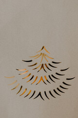 christmas tree made of gold decor on a kraft paper background with two gifts tied with a gold ribbon