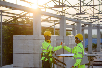 Engineers and Asian construction workers wear safety clothing and safety harnesses. Looking at the structural design at the construction site