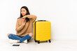 © Asier - Young chinese traveler woman sittting on the floor with a suitcase isolated showing a timeout gesture.