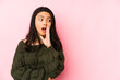 © Asier - Young chinese woman isolated on a pink background is saying a secret hot braking news and looking aside