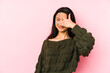 © Asier - Young chinese woman isolated on a pink background blink at the camera through fingers, embarrassed covering face.