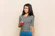 © Asier - Young asian woman holding an apple confused, feels doubtful and unsure.