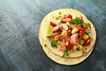 Salmon fish tacos with mango, avocado, tomato, spring onion and lime. Mexican food