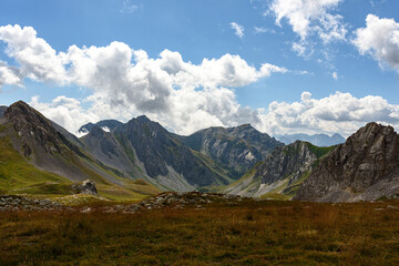 Wall Mural - Mountain range in the alps in which you can see the clouds just at the top and the blue sky above the clouds. In the foreground you can see the floor of the mountains on this side of the valley