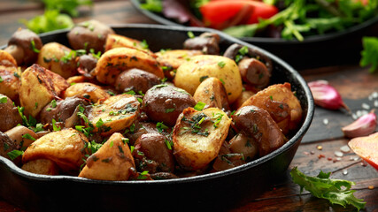 Wall Mural - Baked potato with mushrooms and herbs in iron cast pan on wooden table