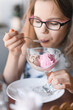 © Ekaterina - Balls of pink and beige ice cream balls zre melting in a creamer on the background of a blurry portrait of a teenage girl.