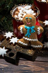 Wall Mural - gingerbread man cookies and hot chocolate on wooden background, vertical top view