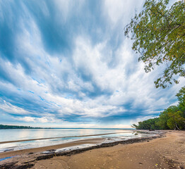 Wall Mural - dramatic autumn landscape with clouds, sandy river bank with fallen leaves.