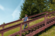© Андрей Рыков - Ten year old caucasian girl walking up wooden stairs in green city park on sunny summer morning. The theme of moving to the future.