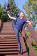 © Андрей Рыков - Beautiful ten year old caucasian girl stands on wooden stairs in city park doing standing split on sunny morning. Outdoor sport theme.