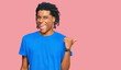 © Krakenimages.com - Young african american man wearing casual clothes smiling with happy face looking and pointing to the side with thumb up.