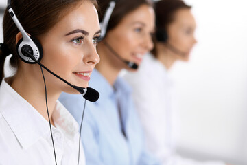 Call center. Group of operators at work. Focus at beautiful business woman in headset