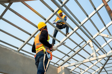 Wall Mural - Roofer builder worker attach metal sheet to new roof on top roof,Unfinished roof construction.