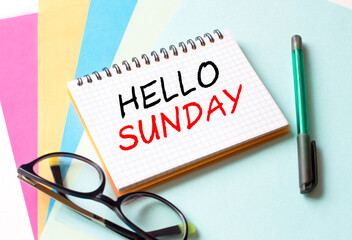 The Notepad with the text Hello Sunday is on colored paper with glasses and a pen