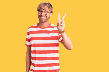 Handsome caucasian man with beard wearing casual clothes and glasses showing and pointing up with fingers number two while smiling confident and happy.