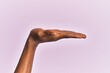 © Krakenimages.com - Arm and hand of black middle age woman over pink isolated background with flat palm presenting product, offer and giving gesture, blank copy space