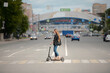 © pressmaster - Side view of young female standing on electric scooter and moving down crosswalk