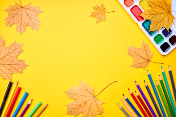 Wall Mural - education and stationery concept. above view for yellow desk. decorated fall leaves and color pencils, markers and other tools. empty space for design