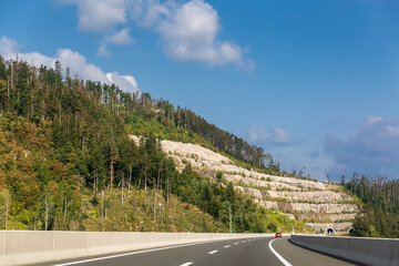 Panoramic view of entrance of tunnel in the mountains of Croatia. Beautiful landscape with mountain and forest, highway with red car