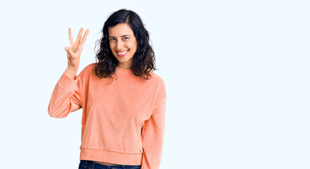 Wall Mural - Young beautiful hispanic woman wearing casual clothes showing and pointing up with fingers number three while smiling confident and happy.