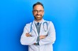 © Krakenimages.com - Handsome middle age man wearing doctor uniform and stethoscope happy face smiling with crossed arms looking at the camera. positive person.