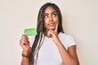 © Krakenimages.com - Young african american woman with braids holding birth control pills serious face thinking about question with hand on chin, thoughtful about confusing idea
