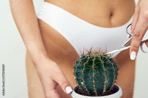 Fotografía The girl cuts a large cactus with scissors in the groin area