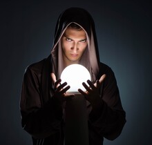 Young Wizard With Crystal Ball In Dark Room