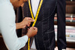 Profesional tailor making bespoke suit for client in his modern stidui