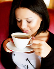 Wall Mural - young woman sitting in a cafe drinking coffee