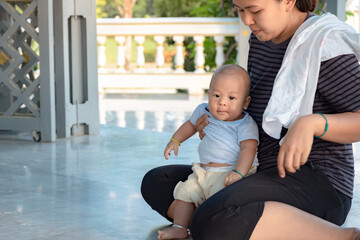 Wall Mural - Happy mother and Asian newborn baby boy playing in summer day on the nature. Recreation family concept. Child in beautiful mom embrace cuddling with tenderness. Breastfeeding or development.