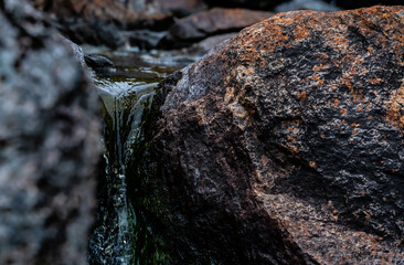 Wall Mural - Close up of pure glacier water running through a crack in the rocks down a stream.