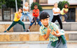 © JackF - Portrait of preteen boy breakdancer dancing outdoors with children in background.