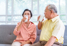 Two Senior Couple Is Drinking Milk While Relaxing On A Sofa Living Room For Retiredment Wellness And Healthy Lifestyle Concept.