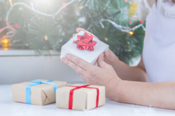 Christmas gift. Blurred Woman in white sweater holding gift box. New year and holidays concept. Selective focus, noise, Effect blur