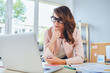 © baranq - Thoughtful woman working looking on laptop working in small office