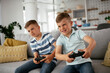 © JustLife - Happy brothers playing video games. Young brothers having fun while playing video games in living room.