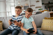 © JustLife - Happy brothers playing video games. Young brothers having fun while playing video games in living room.