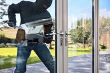 Burglar Breaking Into A House Via A Window With A Crowbar