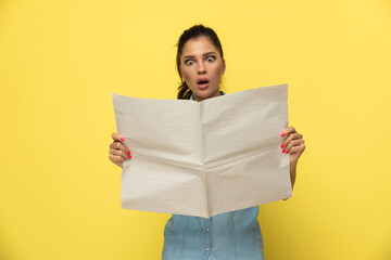 Wall Mural - Amazed casual woman reading newspaper and gasping