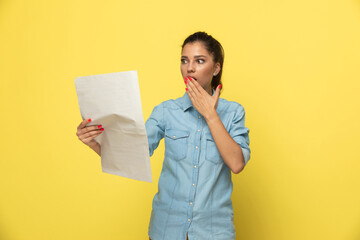 Wall Mural - Shocked casual woman reading newspaper and covering her mouth