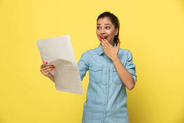 Wall Mural - Surprised casual woman reading newspaper and gasping, laughing