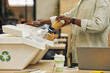 © Seventyfour - Cropped portrait of unrecognizable African-American man putting paper cup into waste sorting bin in office, copy space