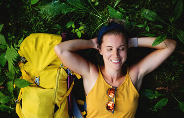 Wall Mural - top view of woman hiker lying on the ground outdoors in forest, resting.