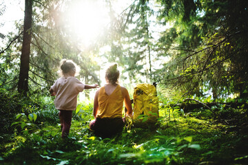 Wall Mural - rear view of mother with small daughter outdoors in summer nature, resting.
