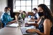 © Halfpoint - Business people with face masks indoors in office, back to work after coronavirus lockdown.