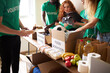 © alfa27 - diverse volunteers collecting food and clothes donations in warehouse, multi-ethnic team of volunteers holding donations boxes in a large warehouse, they are putting clothes in boxes